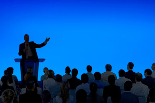 person speaking on stage to a crowd
