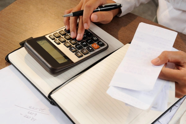 person holding receipts with calculator