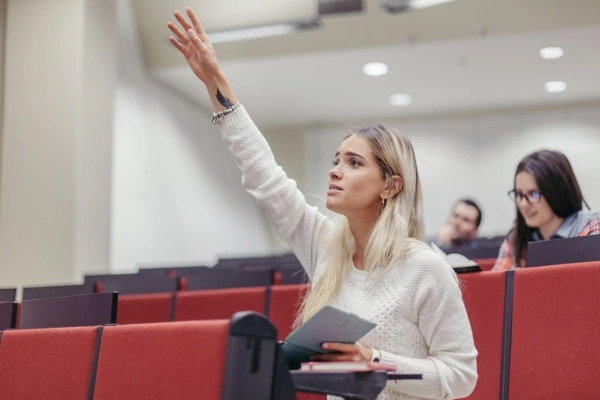 woman sitting in a lecture with hand raised