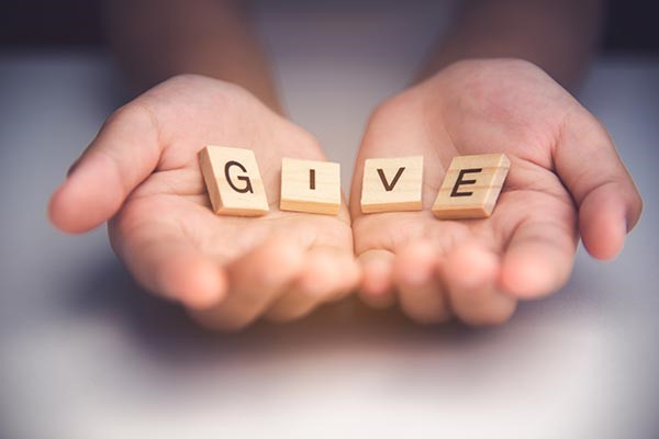 hands holding letter blocks spelling "GIVE"