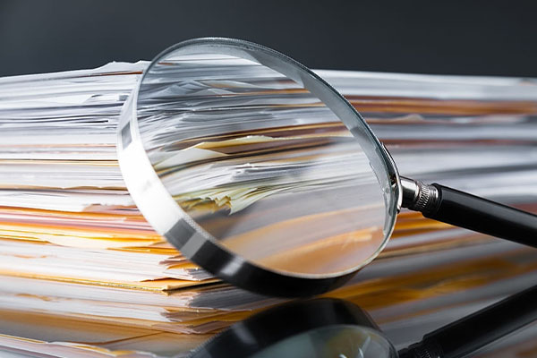 magnifying glass on top of stack of papers