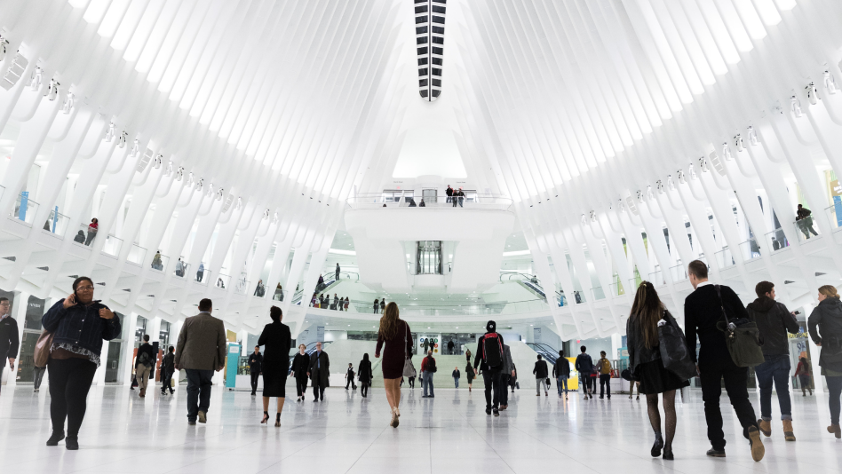 A vast white atrium leading people to and from a train station.