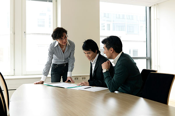 three people having a discussion around a table