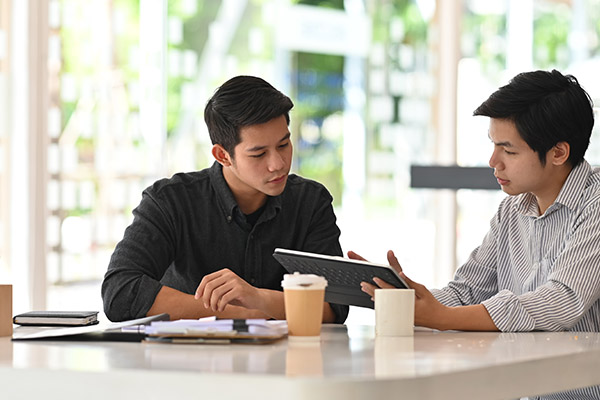 two men looking at a tablet